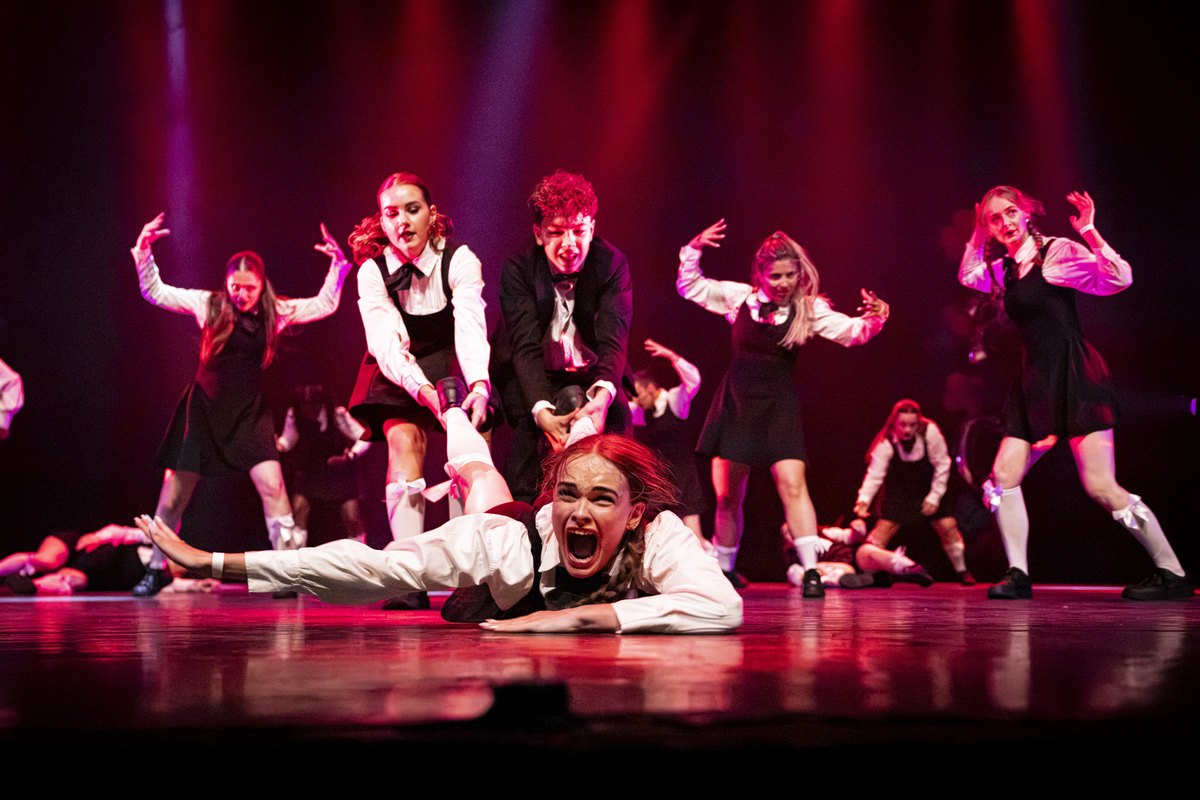 Dansgroep in rood licht op het podium